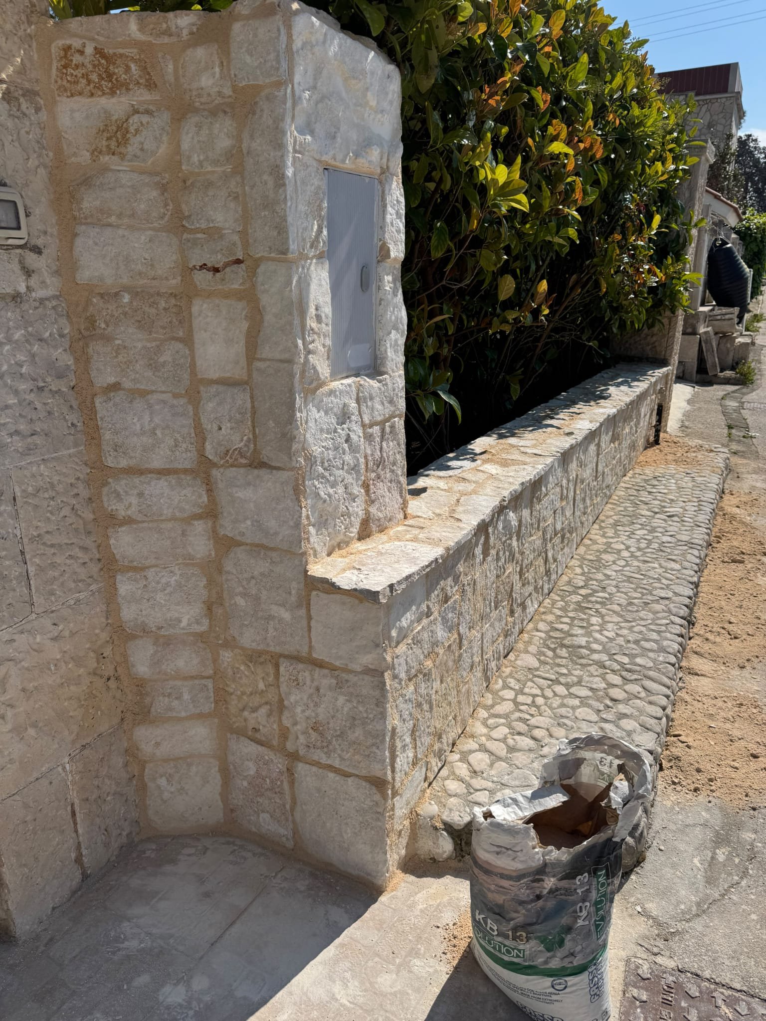 Muretto in pietra con pilastro e stuccatura delle fughe, lavorazione a mano in Puglia